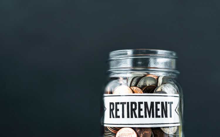 Money background of glass jar filled with coins and RETIREMENT message