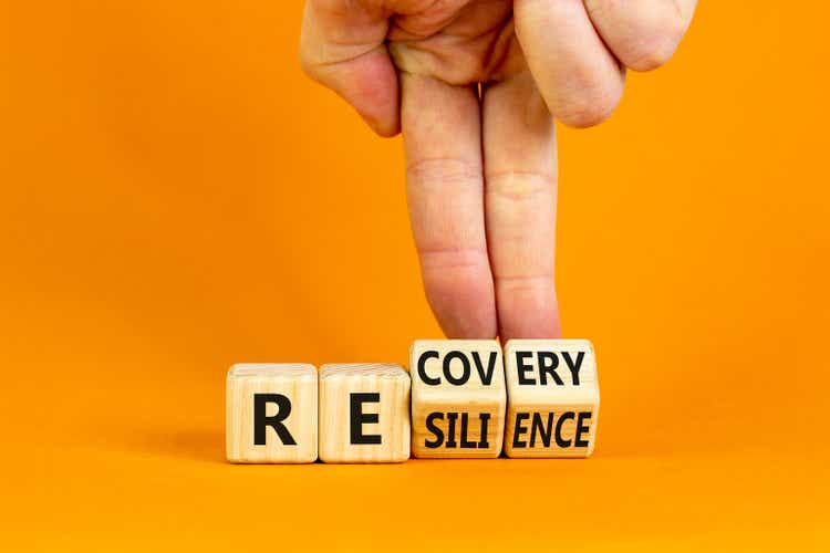 Recovery and resilience symbol. Businessman turns cubes and changes the word "recovery" to "resilience". Beautiful orange background. Business and recovery - resilience concept. Copy space.