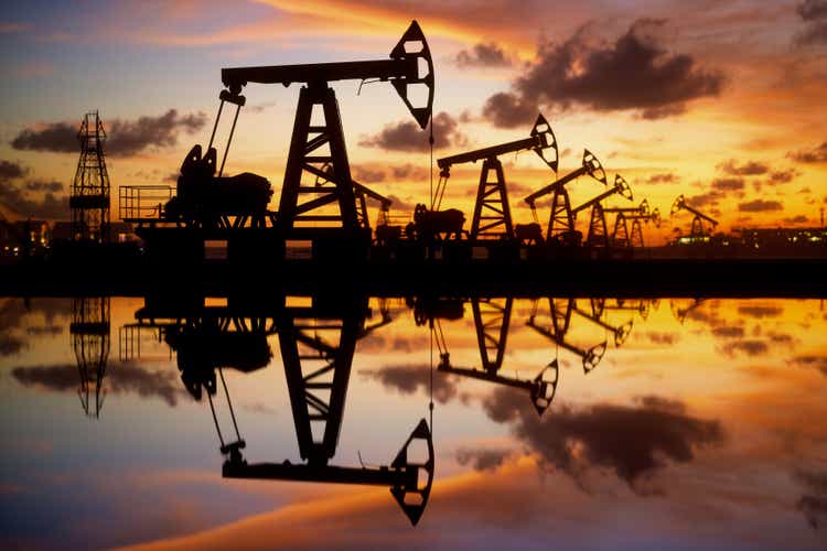 Oil pump and drilling machine at sunset by the sea