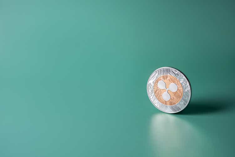 Ripple XRP cryptocurrency coin on green background with copy space