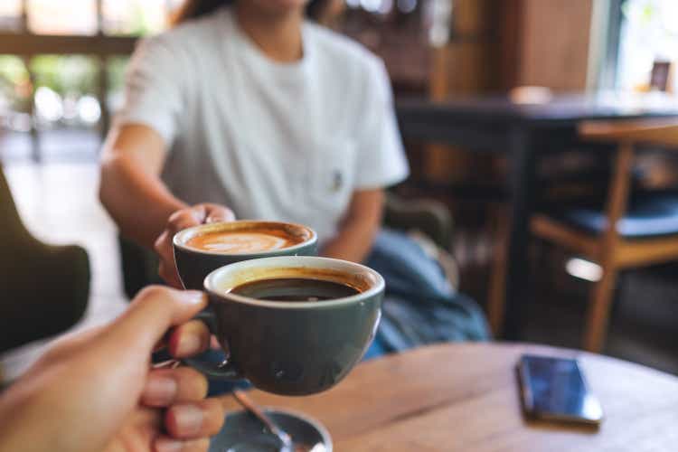 ein Mann und eine Frau klinken Kaffeebecher im Café