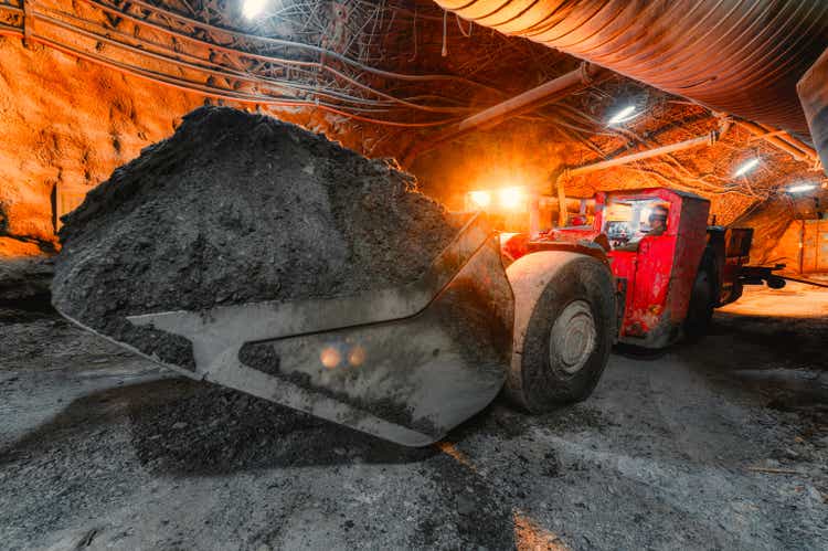 An underground loading machine transports a full bucket of ore.  Special low-profile equipment for underground work
