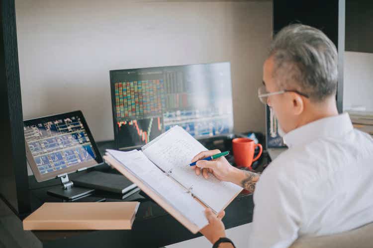 asian senior chinese man working at home with stock exchange market multiple computer monitor monitoring market trend