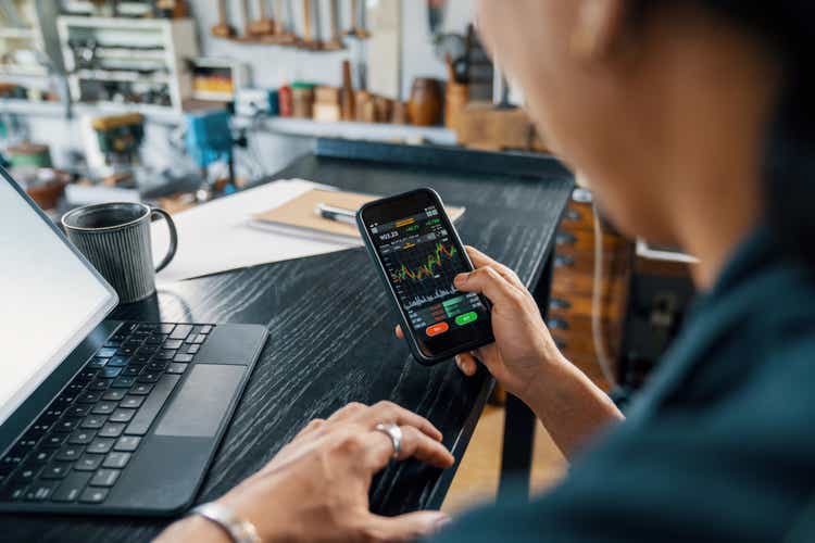 Mid adult man using a smart phone to monitor his cryptocurrency and stock trading