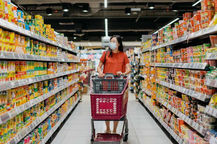 Asian woman with face mask and face shield shopping for groceries in supermarket