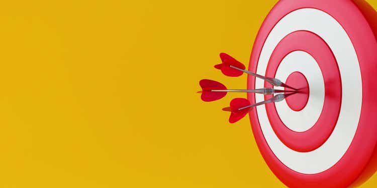 Close up red dart hitting target on yellow background.