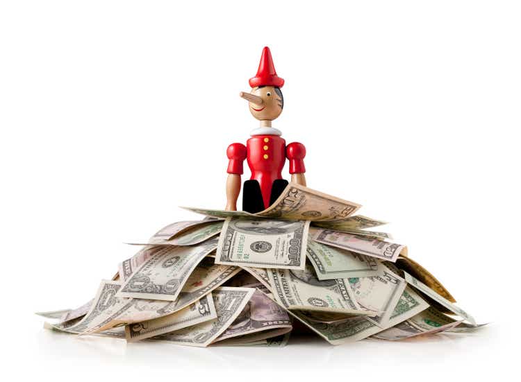 Pinocchio in piedi su una pila di dollari USA