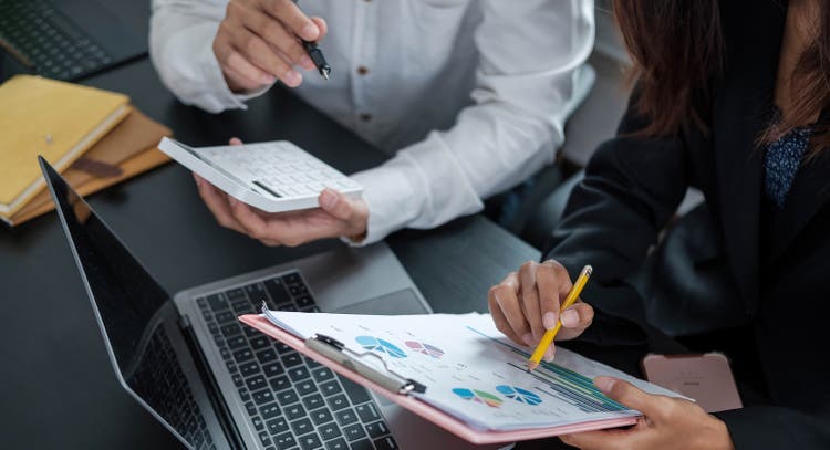 Close up Businessman and partner using calculator and laptop for calaulating finance, tax, accounting, statistics and analytic research concept