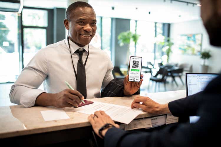 Businessman showing his vaccine passport at the hotel reception