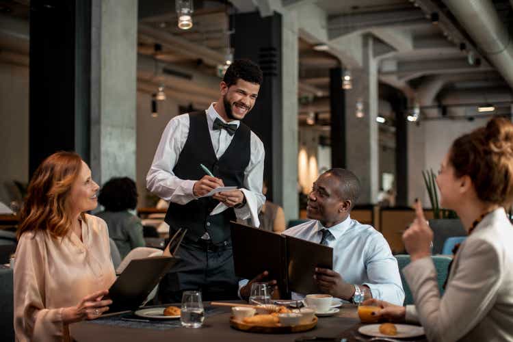 Group of business people ordering food and drinks from the waiter