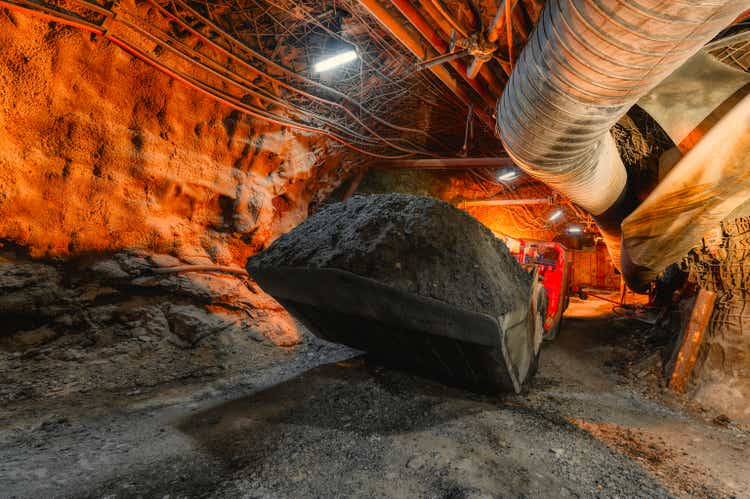 An underground loading machine carries a full bucket of ore. Special low-profile equipment for underground work