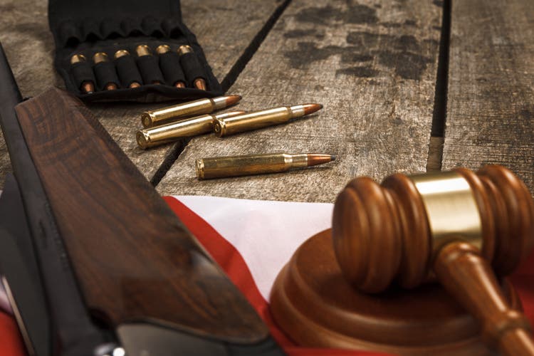 Wooden judge gavel and hunting rifle over USA flag on wooden background