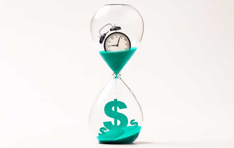 Alarm clock inside hourglass and countdown to US dollar sign , Money and time management concept.