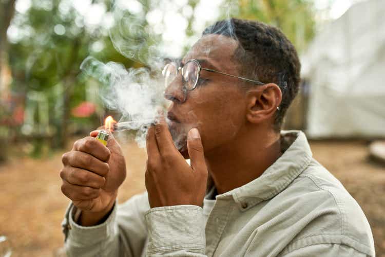 Close view of young afro guy lighting a joint