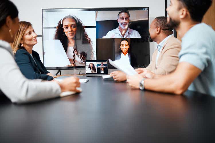 Cropped shot of a diverse group of businesspeople sitting in the boardroom during a meeting with their international colleagues via video chat