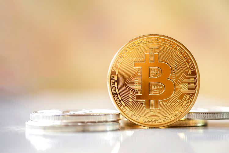 Bitcoin stands in front of a bright blurred background.