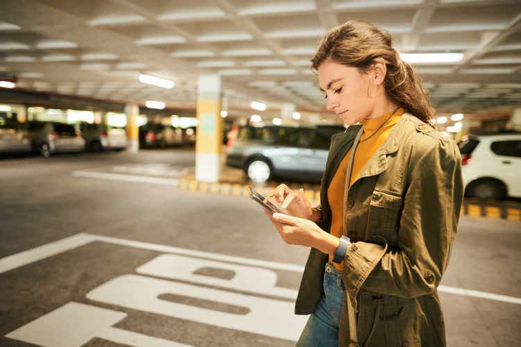 Woman checking a phone app while walking in a parking garage