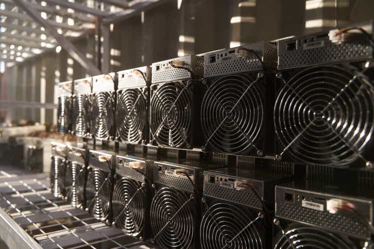 Bitcoin ASIC miners in warehouse. ASIC mining equipment on stand racks for mining cryptocurrency in steel container. Blockchain techology application specific integrated circuit units storage