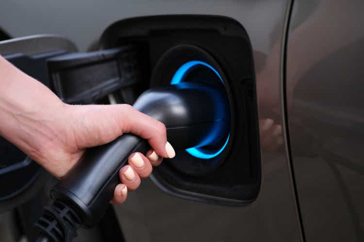 Woman charging car using electric plug closeup