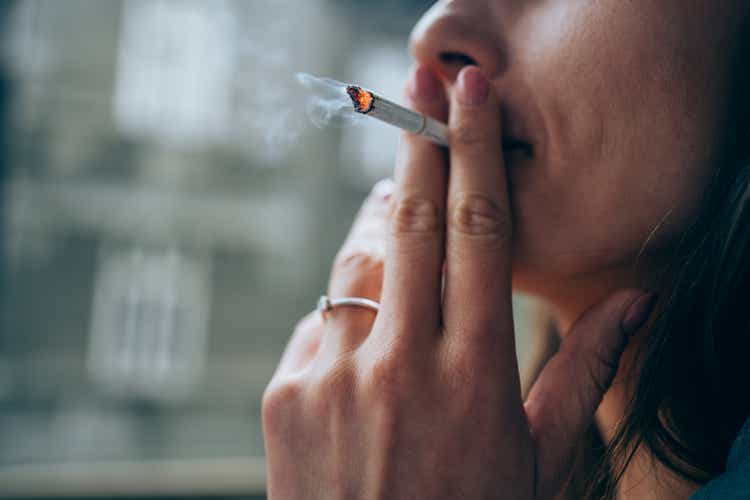 Young woman smoking a cigarette outdoors.