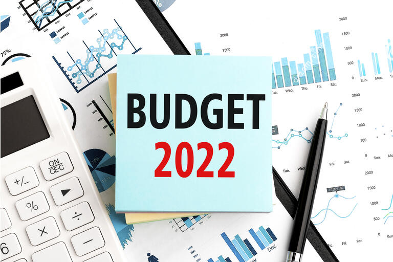 Text BUDGET 2022 on stickers. Pen and calculator on clipboard with charts, documents and graphs. Business plan. Top view.