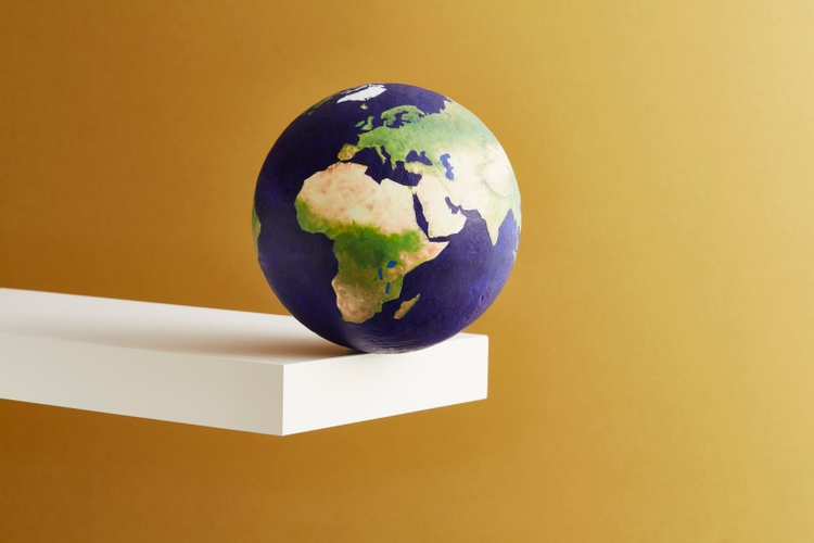 A world globe balanced on the edge of a shelf