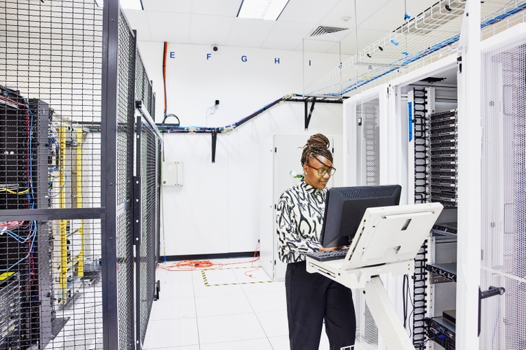 Medium wide angle shot of female computer engineer configuring servers in data center