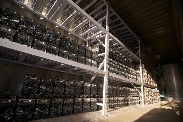 Bitcoin ASIC miners in warehouse. ASIC mining equipment on stand racks for mining cryptocurrency in steel container. Blockchain techology application specific integrated circuit units storage