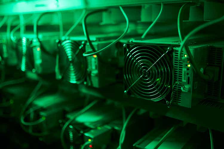 Bitcoin miners in large farm. ASIC mining equipment on stand racks mine cryptocurrency in steel container. Blockchain techology application specific integrated circuit datacenter. Server room lights