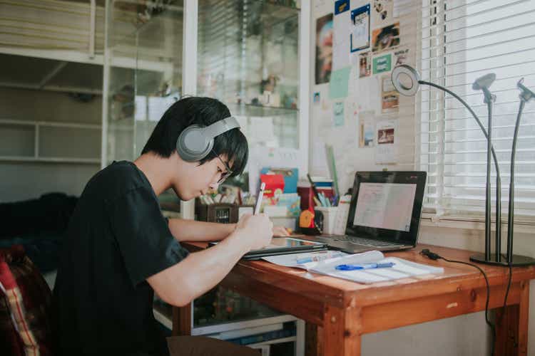 Thai nerd male teenager studying and doing school homework with tablet for Distance learning online education - stock photo