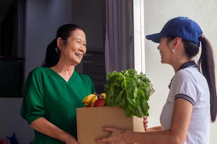 Young woman delivering groceries to senior woman