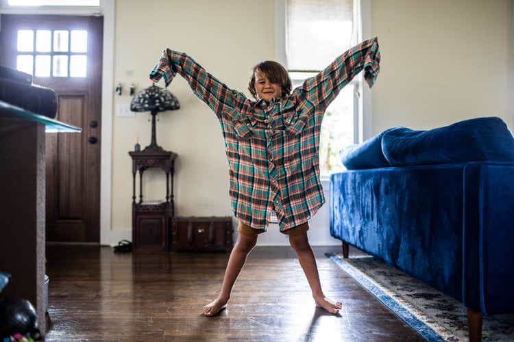 Young boy wearing father"s oversize shirt at home