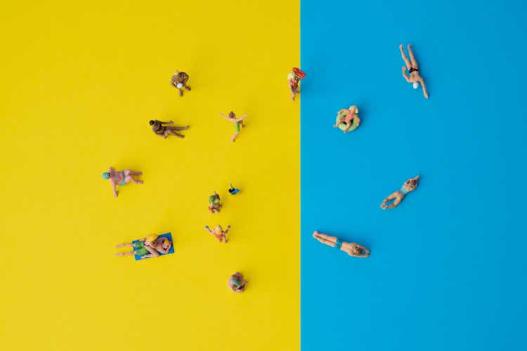 miniature people on yellow and blue paper, holiday situation with swimming or sunbathing people