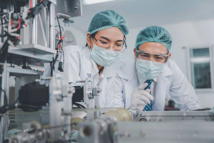 Two Asian doctor or engineer working at clean medical mask production factory, Production hygiene medical manufacturing qaulity inspection concept