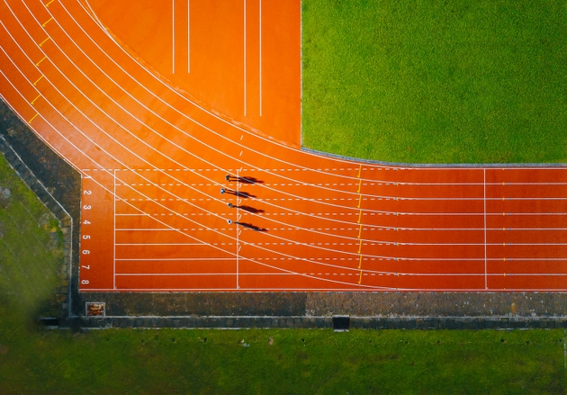 directly above drone point of view asian chinese male athlete running at men"s track rainy late evening in stadium