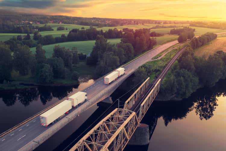 Trucks driving through a countryside landscape at sunset