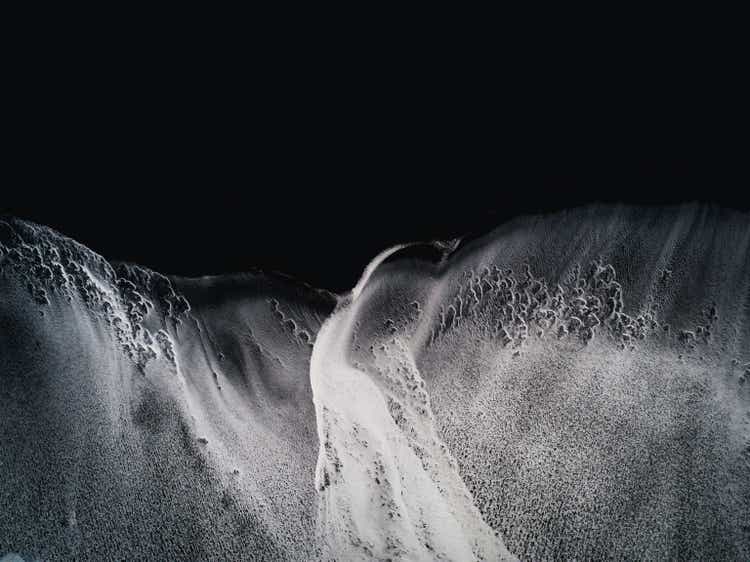 Waves rolling onto a black sand beach seen from a drone point of view, Vik, Iceland