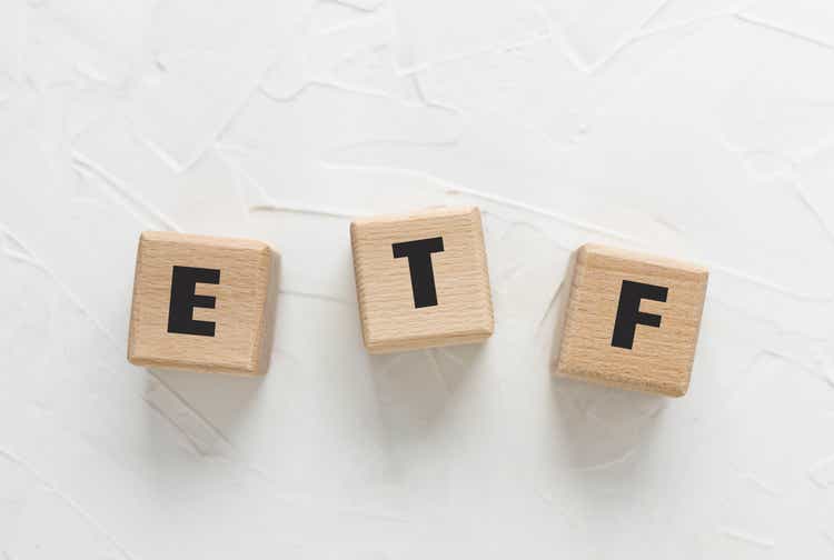 Text ETF on wooden cubes on white textured putty background. Abbreviation of "Exchange Traded Funds". Square wood blocks. Top view, flat lay.