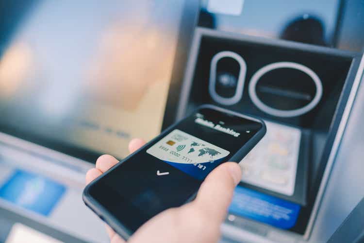 Man at the ATM withdrawing money with smartphone