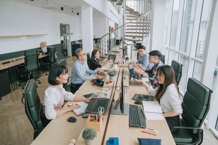 Asian multi-ethic white collar worker busy working and communicate in their office workstation in open plan cheerful and happily