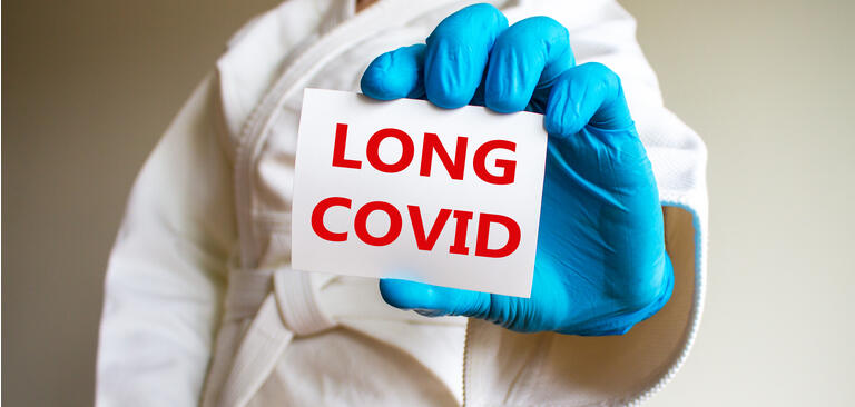 COVID-19 long covid symbol. A young strong man in a white kimono for sambo, jiu jitsu and other martial arts with a blue medical gloves. White card with words "long covid". Long covid concept.