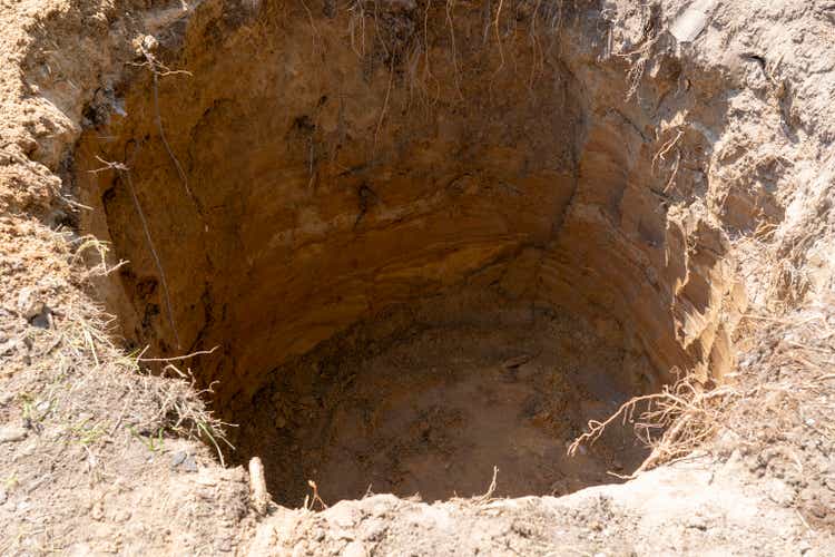 a deep hole is dug in the ground, a sinkhole in the ground