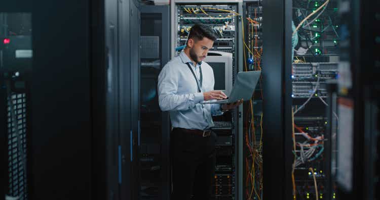 Shot of a young male engineer using his laptop in a server room