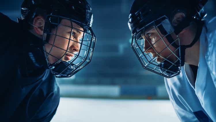 Ice Hockey Rink Arena Spiel Start: Zwei profispieler aggressives Gegenspiel, Stöcke bereit. Intensives Wettbewerbsspiel voller brutaler Energie, Geschwindigkeit, Kraft, Professionalität. Nahaufnahme Porträtaufnahme