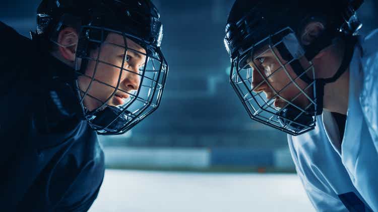 Ice Hockey Rink Arena Game Start: Two Professional Players Aggressive Face off, Sticks Ready. Intense Competitive Game Wide of Brutal Energy, Speed, Power, Professionalism. Close-up Portrait Shot