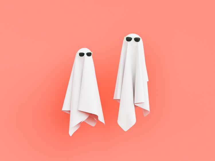 Deux fantômes en tissu avec des lunettes de soleil sur fond pastel rouge