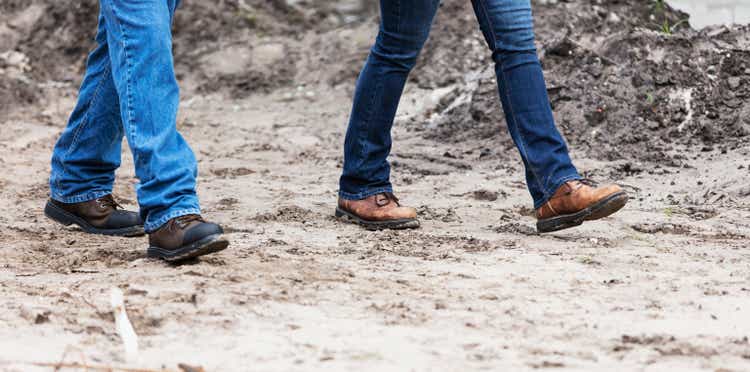 Legs of two construction workers walking at job site