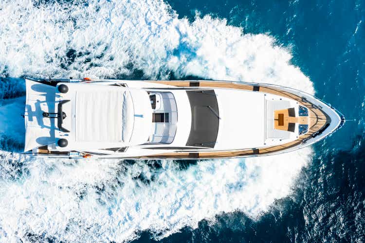 View from above, stunning aerial view of a luxury yacht cruising on a blue water creating a wake. Costa Smeralda, Sardinia, Italy.