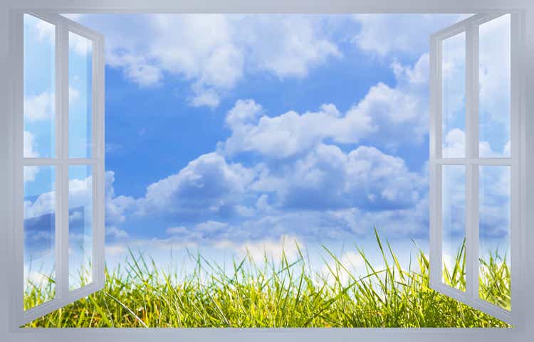 Beautiful green mowed lawn with cloudy sky on background seen through a window - concept image