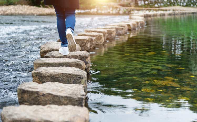 Woman crossing a river on stones